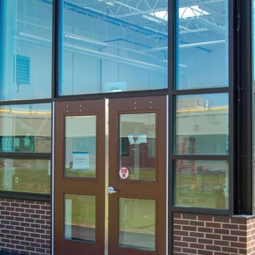 A composite fiberglass door framed with large glass panels and brick detailing. The door, displaying a 