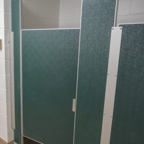Image of a closed bathroom stall with green textured doors and white metallic frames inside a public restroom featuring commercial bathroom partitions.
