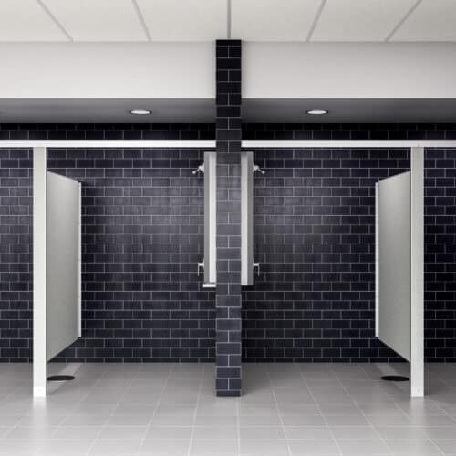 A restroom with sleek black tiled walls features two open stalls, separated by commercial bathroom partitions adorned in crisp white dividers.