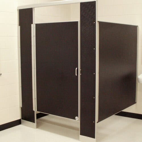 A black restroom stall with a door partially open, situated in a tiled room with white walls, exemplifies the sleek design of commercial bathroom partitions.
