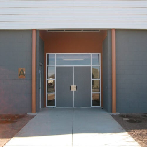 Entrance to a building with double glass doors and a sign labeled 
