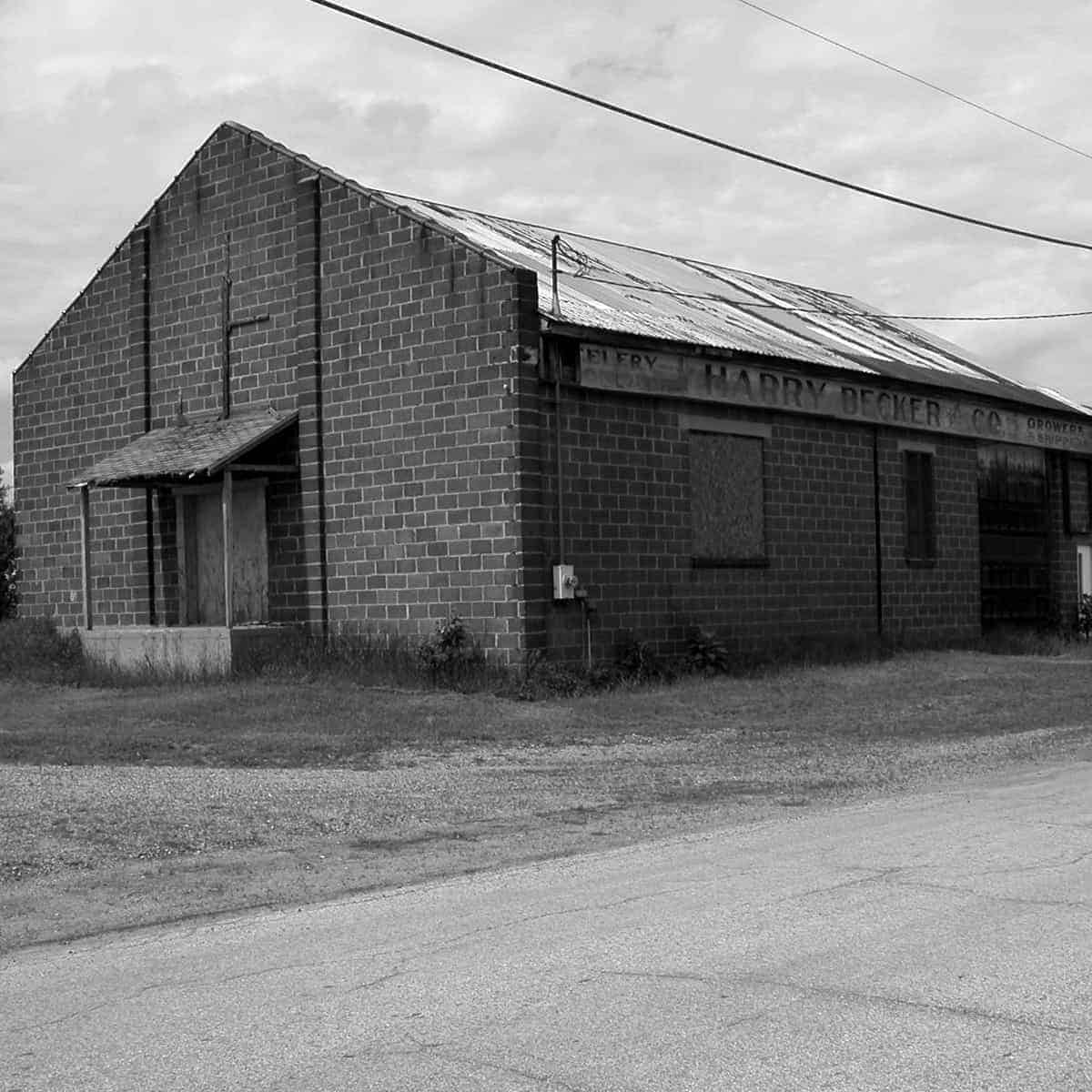 A black and white photo of an old building on the side of the road.