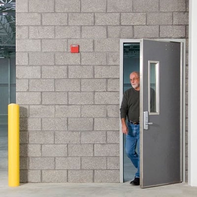 A man overseeing college and university facilities from a warehouse doorway.