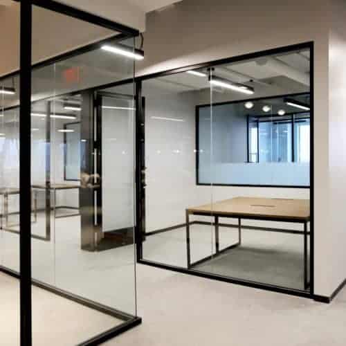 A glass walled office with a table and chairs.