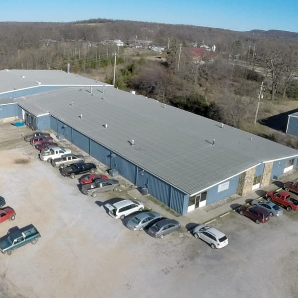 An aerial view of an industrial building with cars parked in front of it.