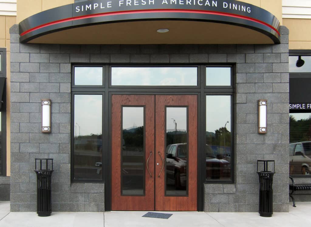 A front view of a restaurant with wood grain front doors.