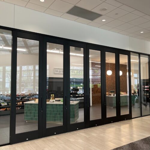 A lobby with a glass sliding door system and a glass wall.