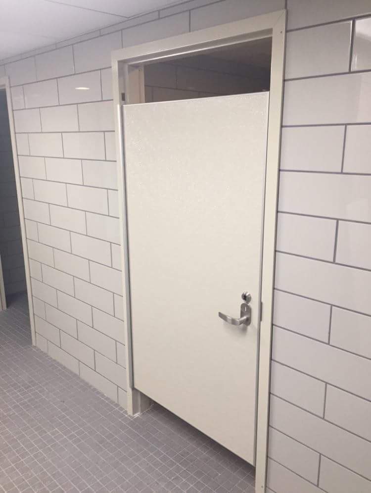 A bathroom with a white door and tiled floor featuring an FRP Aluminum Hybrid Shower and Bathroom Stall Door (SL-175).