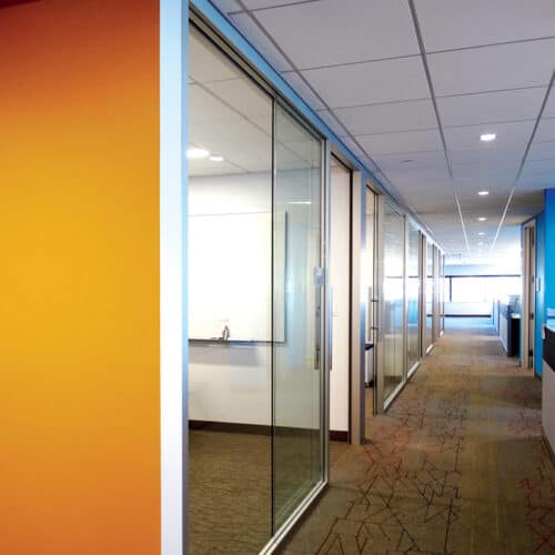 An office with a glass wall and orange walls.