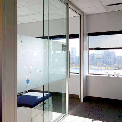 A glass wall in an office with a view of the city.