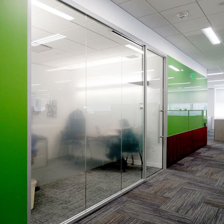An office with green glass walls and glass doors.