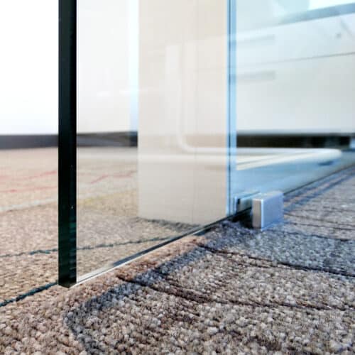 A glass door in an office with a carpet on the floor.