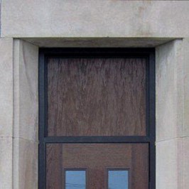A wooden door with moulded panels and a black frame.