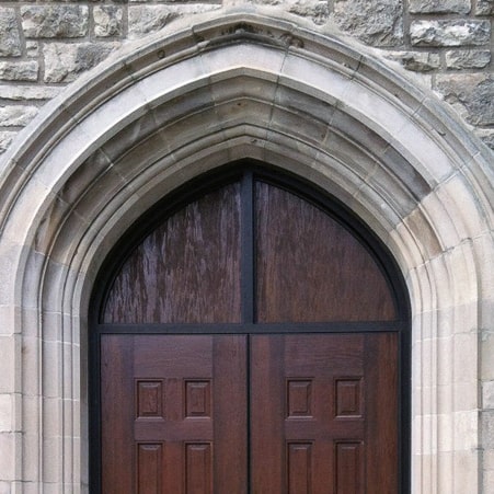 A wooden door with arched windows in front of a stone building, featuring SL-38 architectural panels.