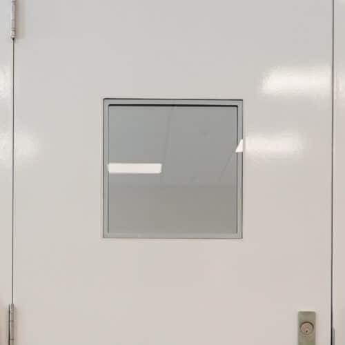 A white door with a square window on it.