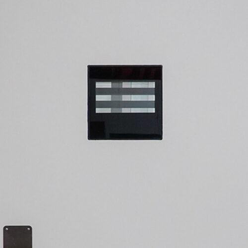 A white wall with a black square on it.