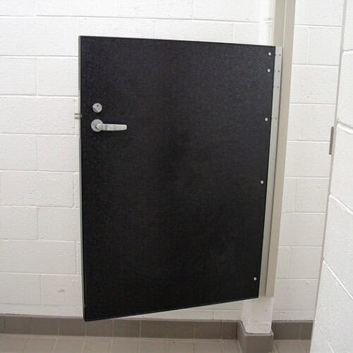 A black half-door installed in a white tiled wall; it has a silver handle and latch.