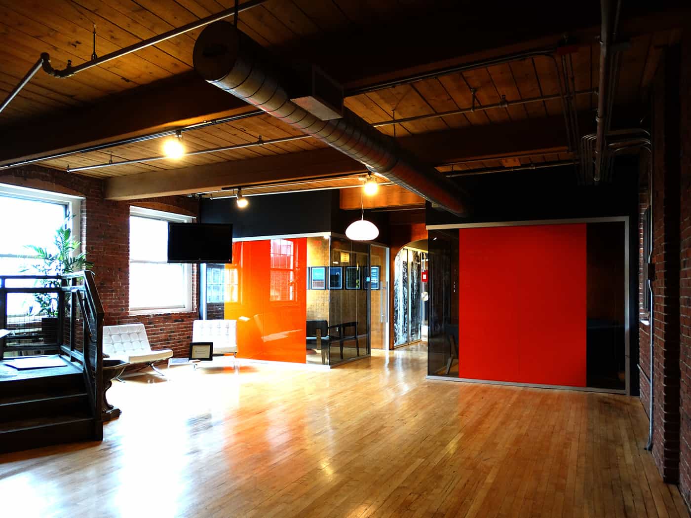 A large room with a wooden floor and glass walls with a red treatment.