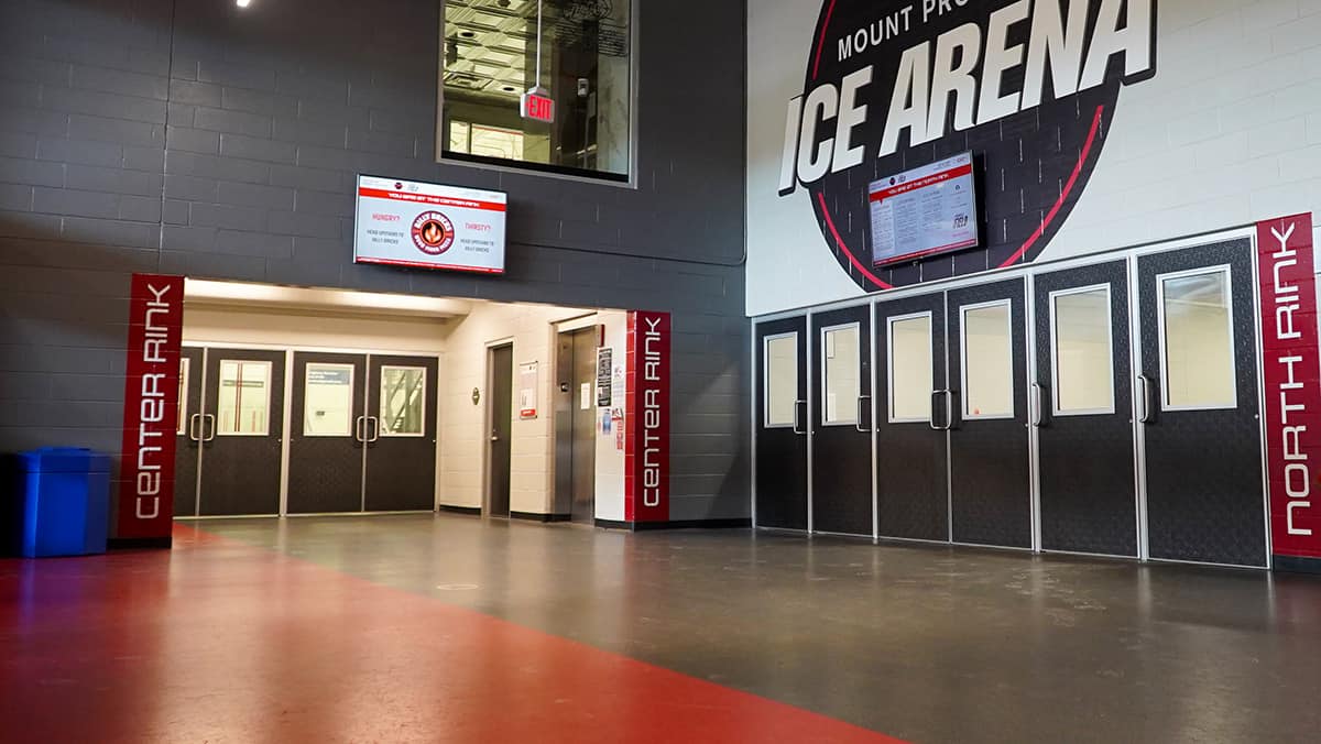 A lobby with Special-Lite fiberglass doors and a large Ice Arena logo on the wall above them.