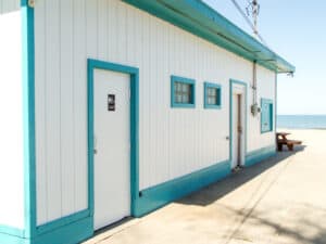 A small building in the park with white walls and light green trim.