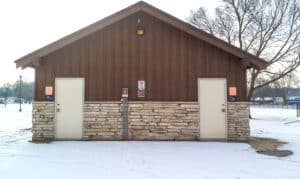 A brown building with two doors located near a park.