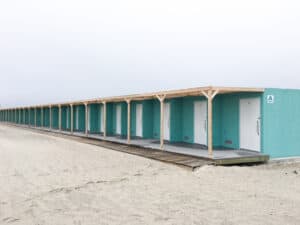 A row of green beach changing rooms.