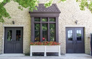 The front of a building with two doors and a flower box in a park.