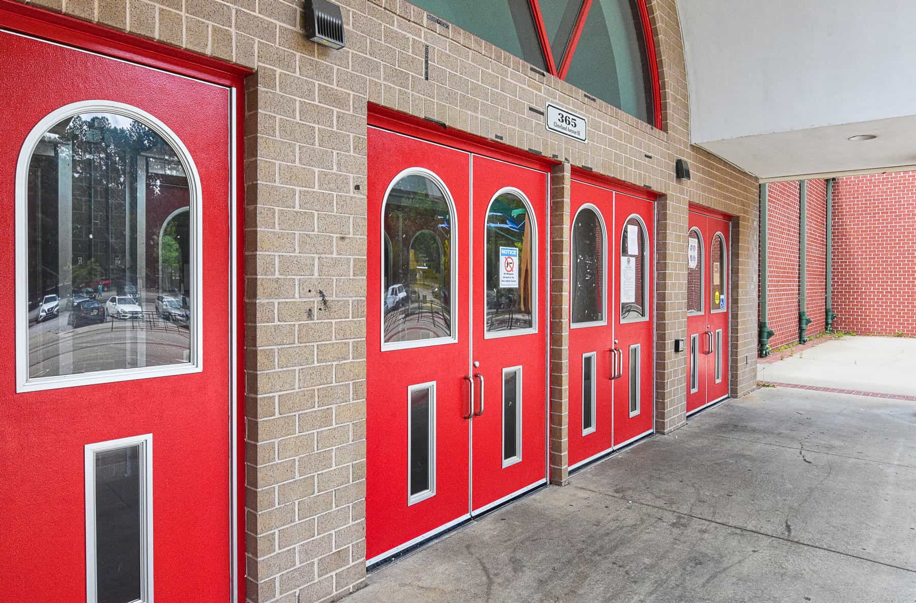 A group of commercial red doors in front of a brick building.