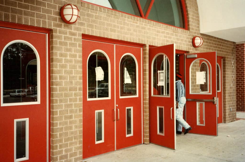 A person walks through a pair of open, red doors. 