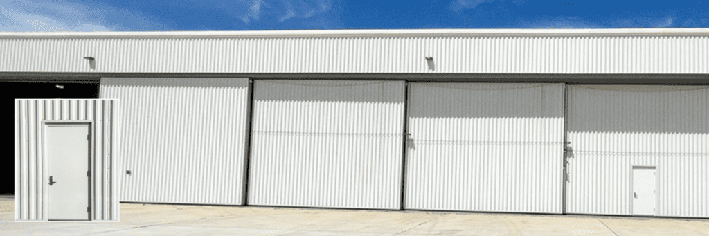 A white hangar with a closeup of a white door under a blue sky.