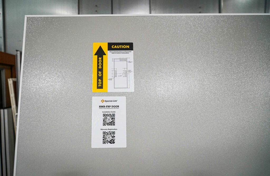 An HMR-FRP Door, with a light grey face, and labels showing Top of the Door and QR codes. 