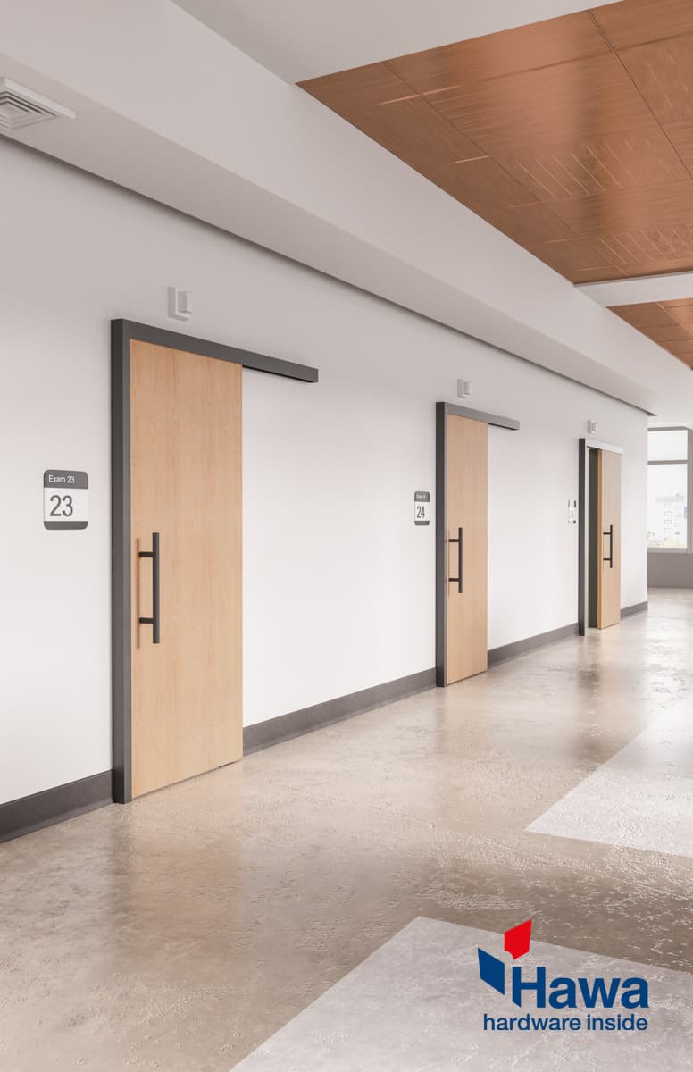 A hallway with a door equipped with the Surface Mounted Sliding Door System. Hawa logo in the lower right corner.