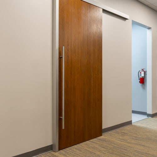 A sliding door in a hallway with a fire extinguisher.