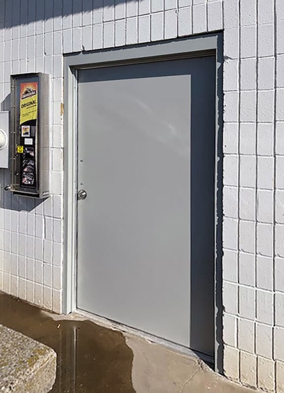 A corrosion-resistant hybrid frp car wash door and fiberglass frame on a white brick wall.