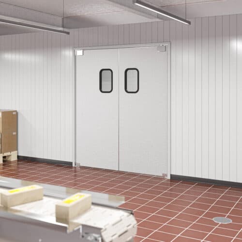 A clean industrial room with white paneled walls, a double traffic door with small windows, a tiled red floor, and boxes on pallets near a conveyor belt.