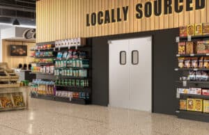 Interior of a grocery store featuring a section labeled "Locally Sourced" with various food products on shelves and double doors in the center.