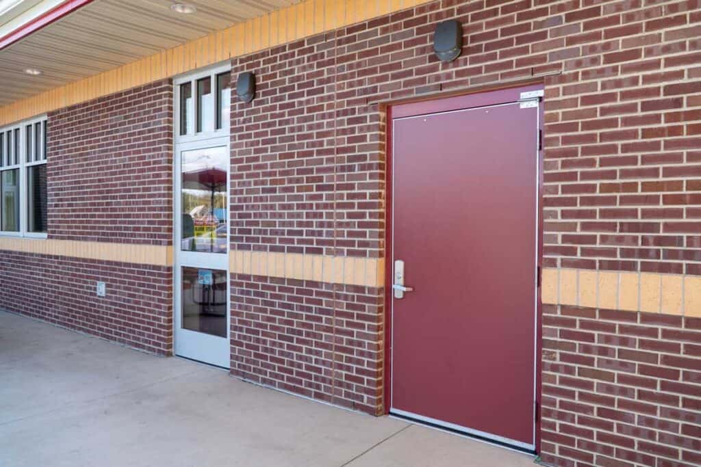 A brick building exterior with a metal door and a glass door, under a covered walkway—an inviting space designed for modern healthcare solutions.
