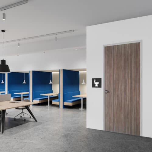 A modern office space with workstations and blue booths, featuring a closed wooden door with a restroom sign on a white wall—perfect for any inspiration gallery.