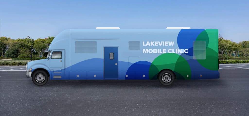 A blue and green mobile clinic vehicle labeled "Lakeview Mobile Clinic" showcases OEM Account Solutions for Modular and Prefabricated Mobile Facilities, parked in an empty lot with trees in the background.